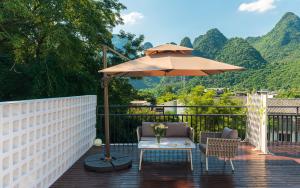 a patio with a table and an umbrella and chairs at Yangshuo MUSE Mountain View Retreat in Guilin