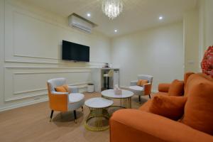 a living room with a couch and chairs and a tv at Station B&B in Tainan