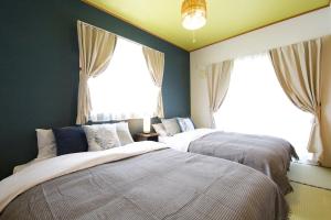 two beds in a room with two windows at カラハーイもとぶ 2-3 in Motobu