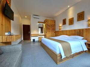 a bedroom with a large bed and a couch at Kamandaka Living in Kuta