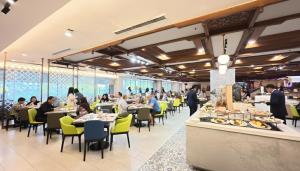 a restaurant with people sitting at tables in a cafeteria at Primula Beach Hotel in Kuala Terengganu