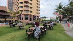 a group of people sitting at tables in a park at Primula Beach Hotel in Kuala Terengganu