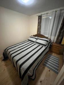 a bedroom with a striped bed with a window at Cabañas Sol y Mar in Puerto Montt