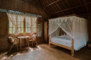 a bedroom with a canopy bed and a table and chairs at Green vanilla mincung 2 in Silebeng