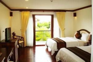a hotel room with two beds and a window at EG Paradise Angkor Villa Hotel in Siem Reap