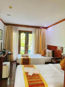 a hotel room with two beds and a window at EG Paradise Angkor Villa Hotel in Siem Reap