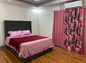 a bedroom with a bed with pink sheets and a clock at Two-Storey Townhouse in Laguindingan
