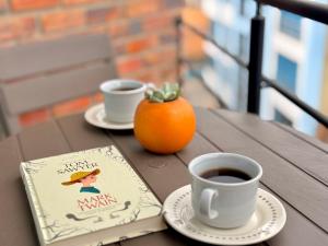 a table with two cups of coffee and a book at Luminoso y Céntrico Loft con Balcón in Sogamoso +4 photos