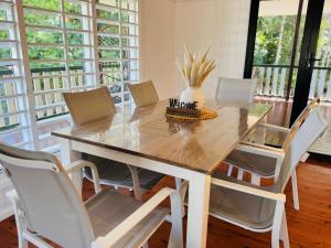 a dining room with a wooden table and white chairs at Kalani - The Heavens View House in Freshwater