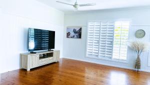 a living room with a flat screen tv and two windows at Kalani - The Heavens View House in Freshwater