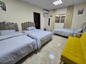 a bedroom with two beds and a yellow chair at NMY Farm1 in Ras al Khaimah