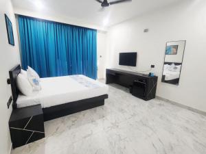 a bedroom with a bed with a blue curtain and a television at La Vida Colva Beach Resort in Colva