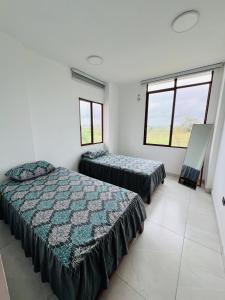 two beds in a room with two windows at Cesar Palace Departamento in Cojimíes