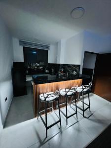 a kitchen with three bar stools and a kitchen with a counter at Cesar Palace Departamento in Cojimíes
