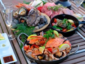 a table topped with plates of seafood and other foods at On The Cliff in Karatsu