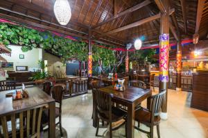 un restaurante con mesas de madera, sillas y plantas en Arya Inn Enny Salon and Spa, en Nusa Lembongan