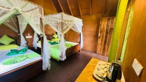 a bedroom with two beds with mosquito nets at Sigiri Aliya Tree house in Sigiriya
