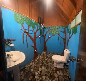 a bathroom with a toilet and a tree mural on the wall at Sigiri Aliya Tree house in Sigiriya