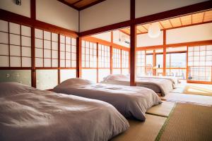 a row of beds in a room with windows at RITO SAKAPORT サウナ付き一棟貸しVilla in Tsushima