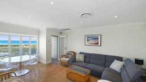 a living room with a couch and a table at Pacific Court 'absolute Beachfront=' in Avoca Beach