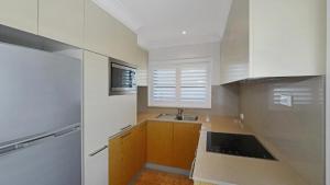 a kitchen with white cabinets and a sink and a window at Pacific Court 'absolute Beachfront=' in Avoca Beach