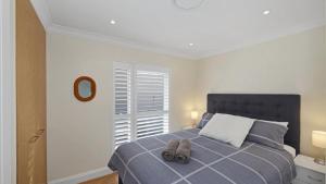 a bedroom with a bed with two shoes on it at Pacific Court 'absolute Beachfront=' in Avoca Beach +6 photos