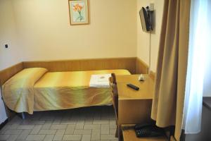 アッシジにあるHotel Fontemaggioのベッド、デスク、デスクが備わる小さな客室です。