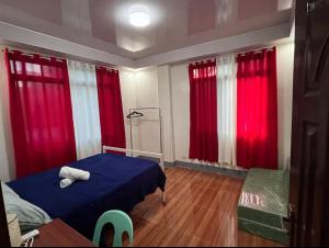 a bedroom with red curtains and a blue bed at Two-Storey Townhouse in Laguindingan +4 photos