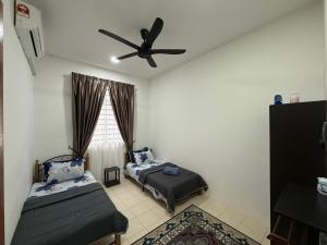 a bedroom with two beds and a ceiling fan at Hasna Homestay Cherating Muslimonly in Kuantan