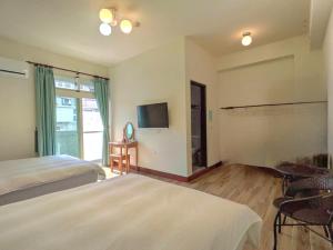 a bedroom with two beds and a flat screen tv at 池上投優榻 Smart living B&B in Chishang