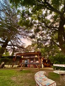 a building in a park with two benches under a tree at Casa del lago in Embalse