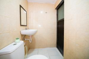a bathroom with a toilet and a sink and a mirror at Behomy Yume Grogol in Jakarta