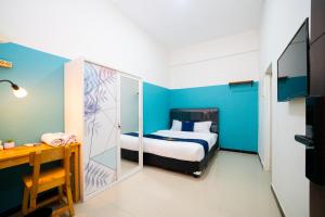 a bedroom with a bed and a blue wall at Behomy Yume Grogol in Jakarta