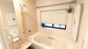 a white bathroom with a tub and a window at MyBound Homestay Zushi in Zushi
