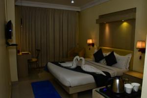 two swans on a bed in a hotel room at The Rass in Kānpur
