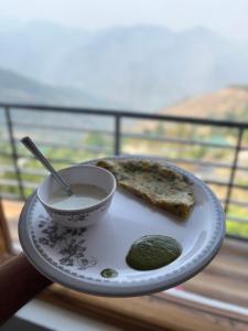 a plate of food with a bowl of soup and a pickle at Ridhi Sidhi cottage in Kīar