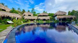 a resort with a swimming pool with thatched huts at Shiva Sunrise Resort in Hikkaduwa