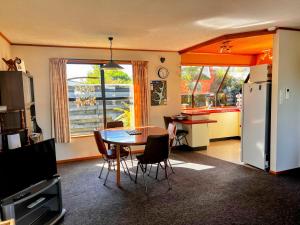 a kitchen and dining room with a table and a refrigerator at Cosy Corner Te Anau in Te Anau