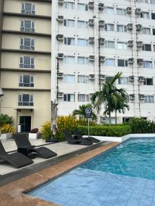 a hotel swimming pool with lounge chairs in front of a building at Avida Aspira Studio 18th in Cagayan de Oro