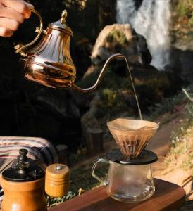 a person is pouring coffee into a tea kettle at Doi Inthanon Waterfall Garden in Ban Sop Mae Klang