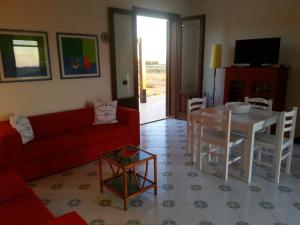 un soggiorno con un divano rosso e un tavolo di Villetta Cala Rotonda a Favignana