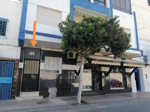 a tree in front of a building with an orange arrow at La esquina in Martil