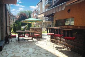 an outdoor patio with tables and chairs and an umbrella at Apartment Danik City Garden in Bansko