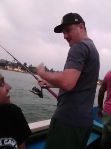 a man standing on a boat holding a fishing rod at Vivid Lanka in Bentota