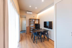 a dining room with a table and chairs and a television at Long Vacation Resort in Fukuoka