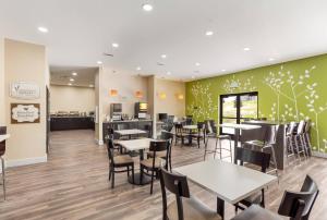 a restaurant with tables and chairs and a kitchen at MainStay Suites Logan Ohio-Hocking Hills in Logan