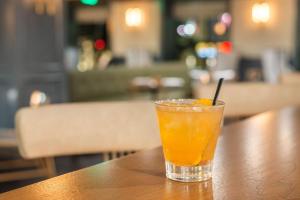 a glass of orange juice sitting on a wooden table at Cambria Hotel Houston Downtown Convention Center in Houston