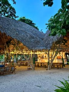 a straw roofed restaurant with tables and chairs at Isla - The Island Experience in El Nido