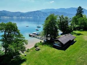 a house on the shore of a lake with boats in the water at Die Tinys - Ferienhäuser am Attersee in Nussdorf am Attersee