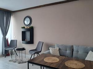 a living room with a couch and a table and a clock at Premium StudioApartment in Borovets Gardens in Borovets